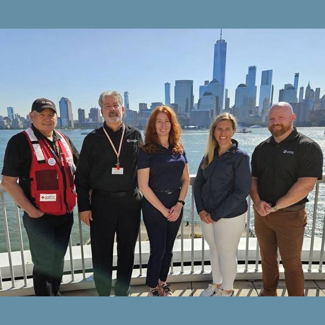 Five Red Cross staff members pose for group pic with city skyline in the background.