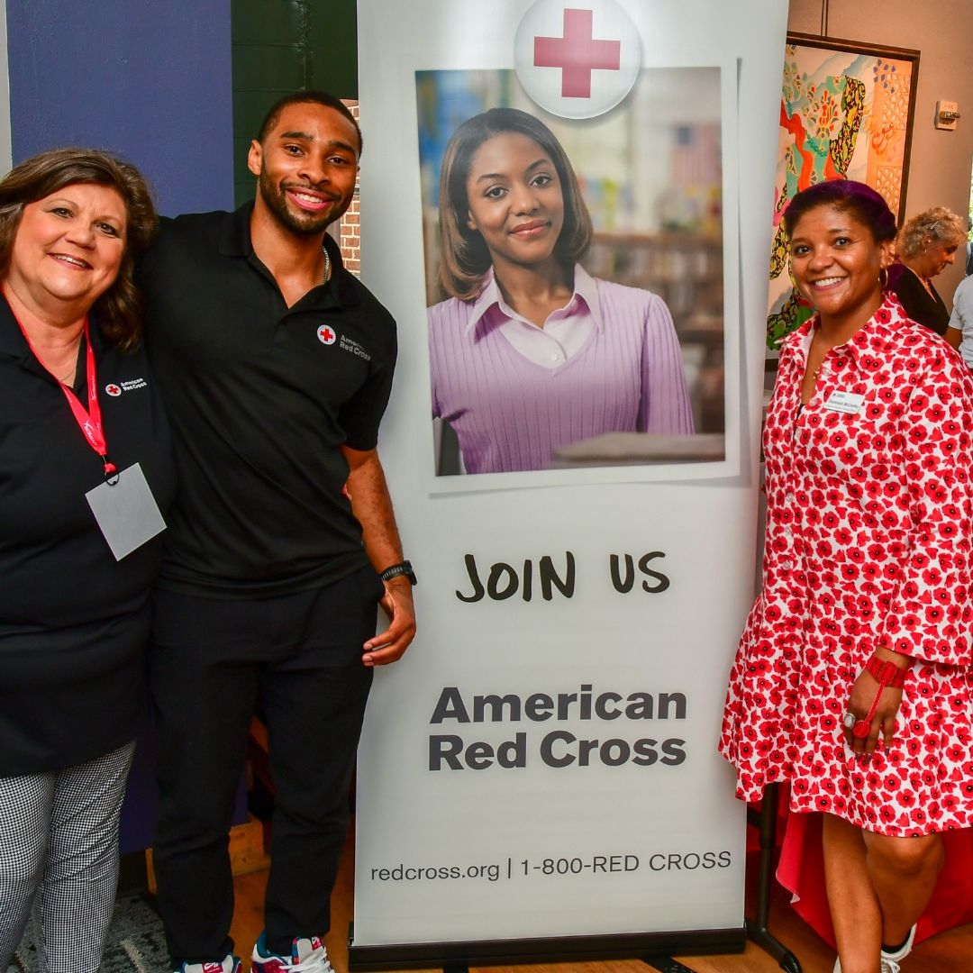red cross volunteers standing in front of youth summit banner