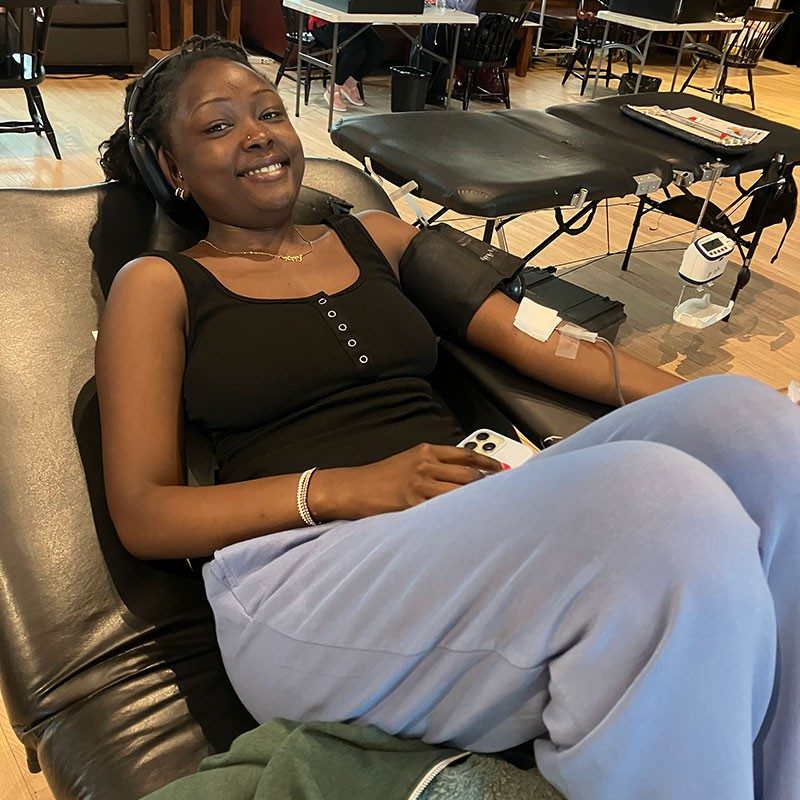 blood donor sitting in a chair smiling and donating blood.