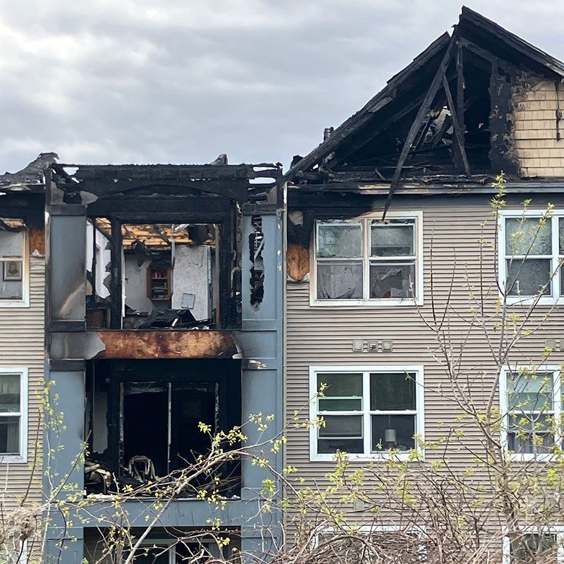 a three story apartment building with fire damage to the top floor.
