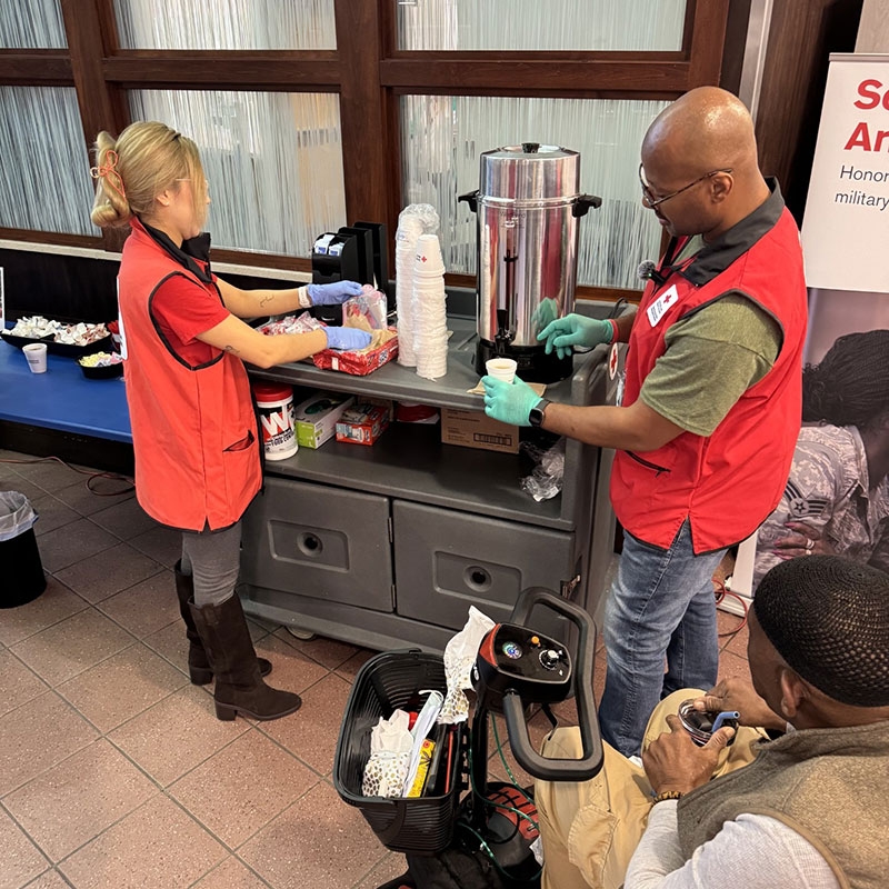two Red Cross volunteers serving coffee to veterans.
