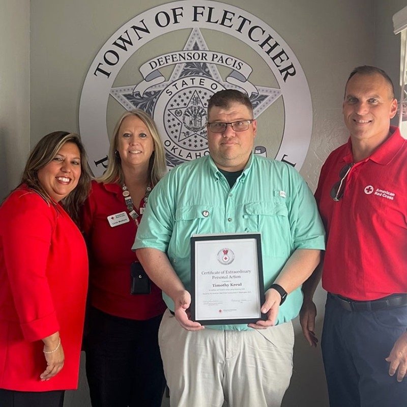 Police Officer Timothy Kreul holding an award  and three others posing for a picture.