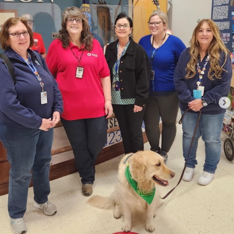 A group of Red Cross volunteers with a dog on a leash. 