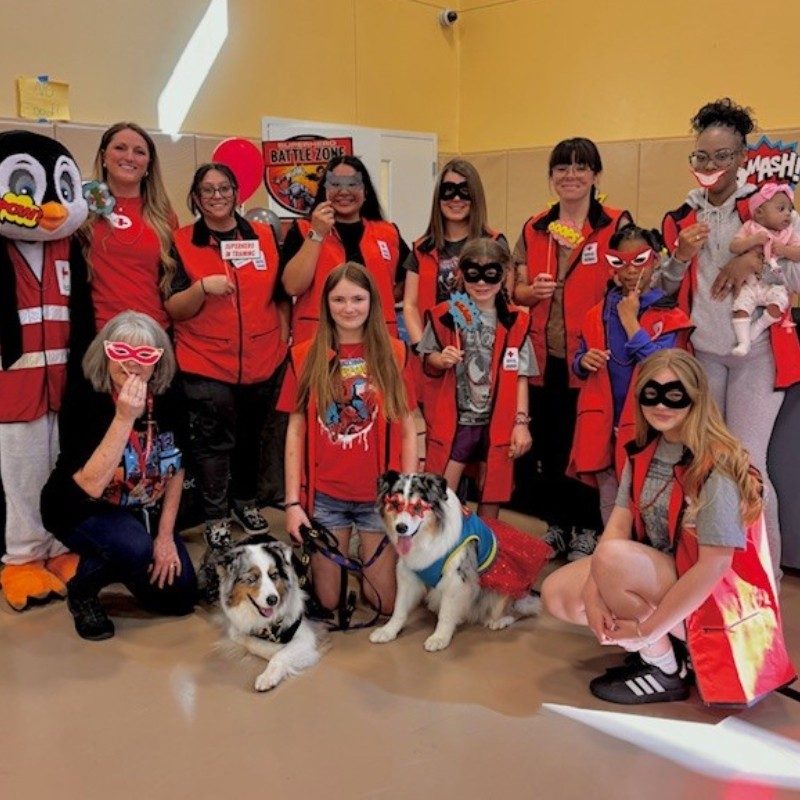 A group of Red Cross volunteers, kids and two dogs posing for a group picture.