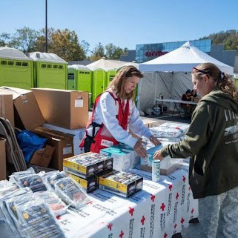 Whitney at a table handing out supplies to a person.