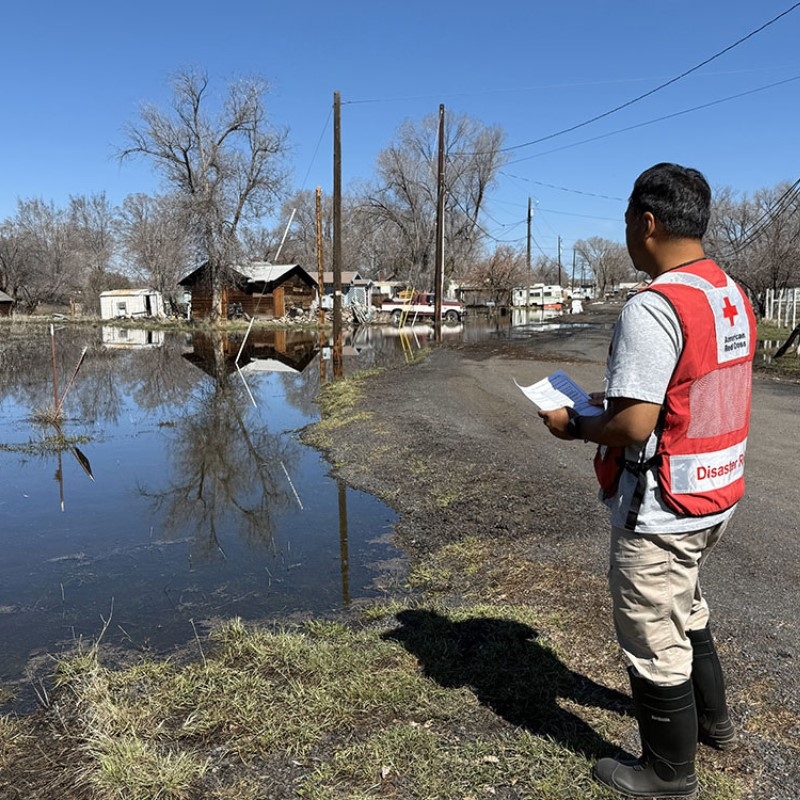 Brian in a Red Cross vest surveying a flooded area.