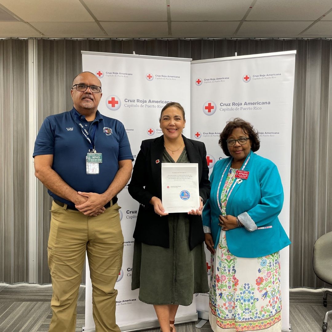 Tres personas de pie frente a una pancarta con certificado