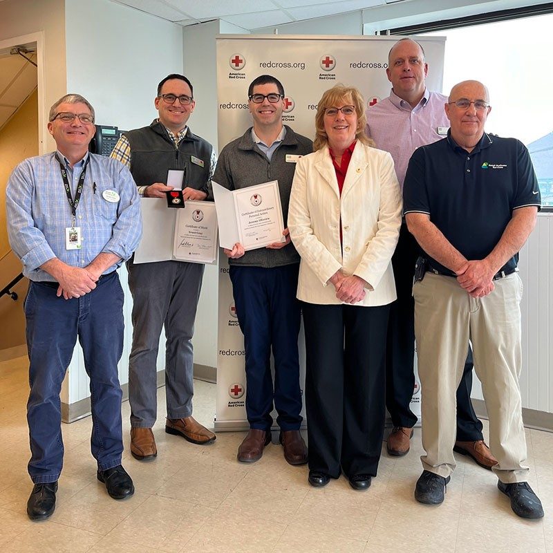 Grant and Jeremy, Stop and Shop employees, displaying their Lifesaving Award while standing next to Red Cross staff.