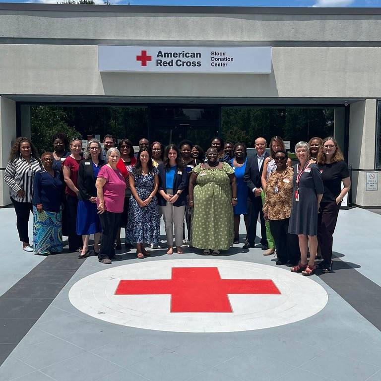 Red Cross and BlueCross employees group pic in front of an American Red Cross Donation Center building.