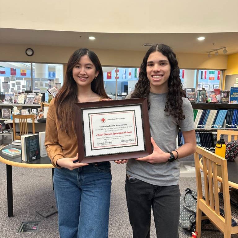 Amanda and Max holding a framed certificate from the Red Cross for organizing the canned food drive.