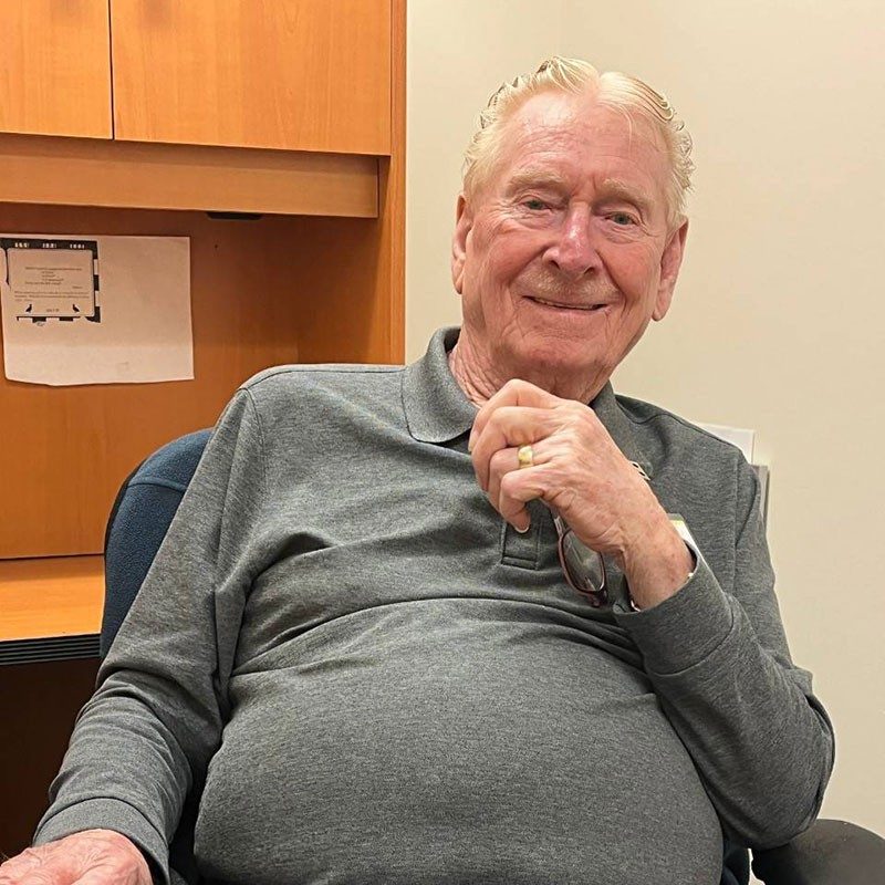 Bill Strader sitting in a chair and smiling.