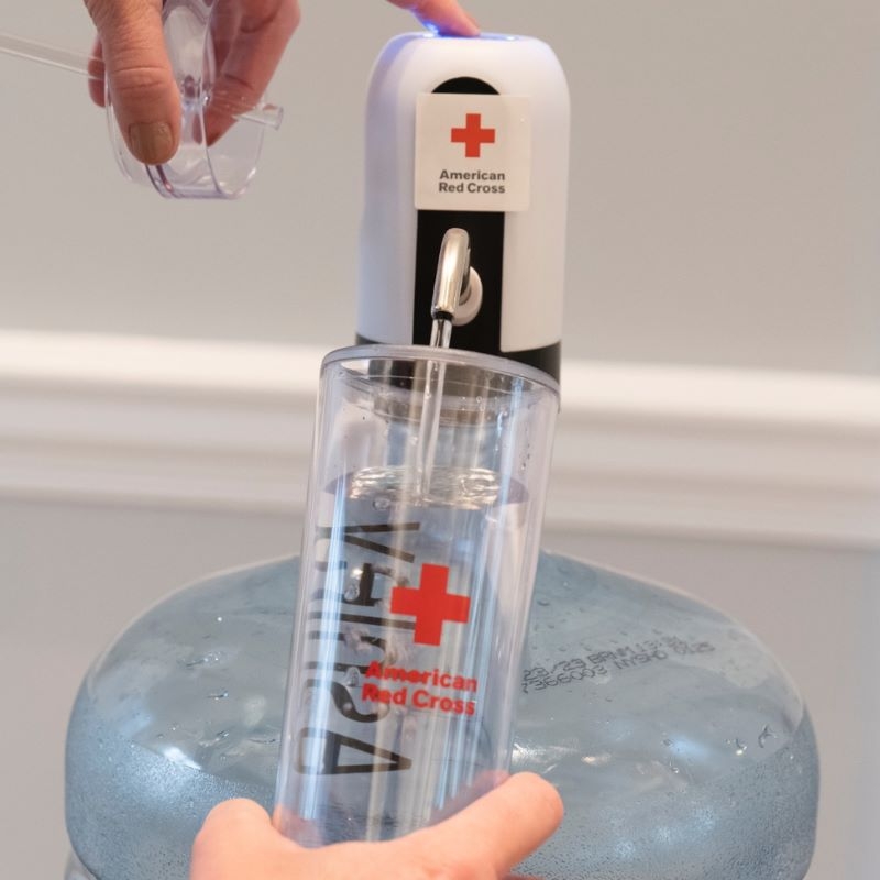 Aa person pushing the button on a water fountain while holding a bottle underneath.