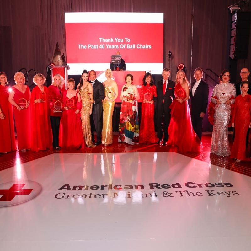 Group of people in formal wear standing in a horizontal line holding awards.