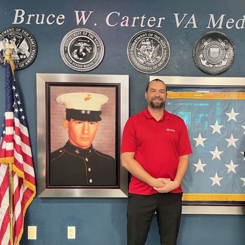 Jeff Wheatley standing next to a portiat of himself in his military uniform.