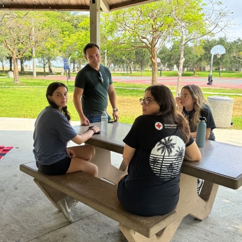 Group of students sitting at a table at a park.