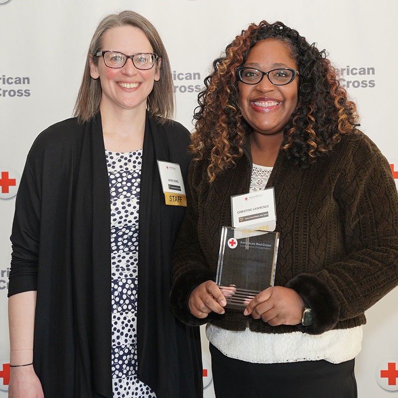Volunteer Christine Lawrence, holds a Red Cross award she received, with Service to the Armed Forces and International Services program manager Jaime Boris.