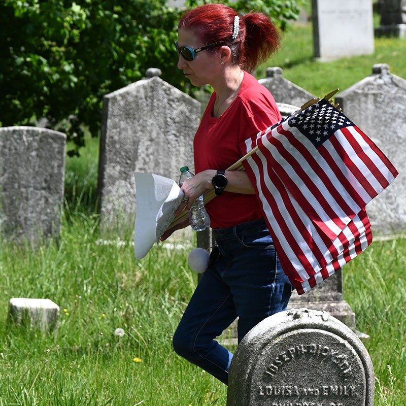 woman carrying american flags at a cemetery.