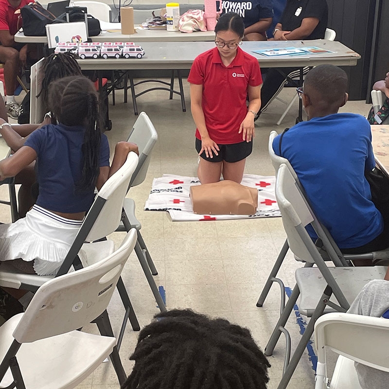 Red Cross counselor teaching cpr to a classroom full of children.