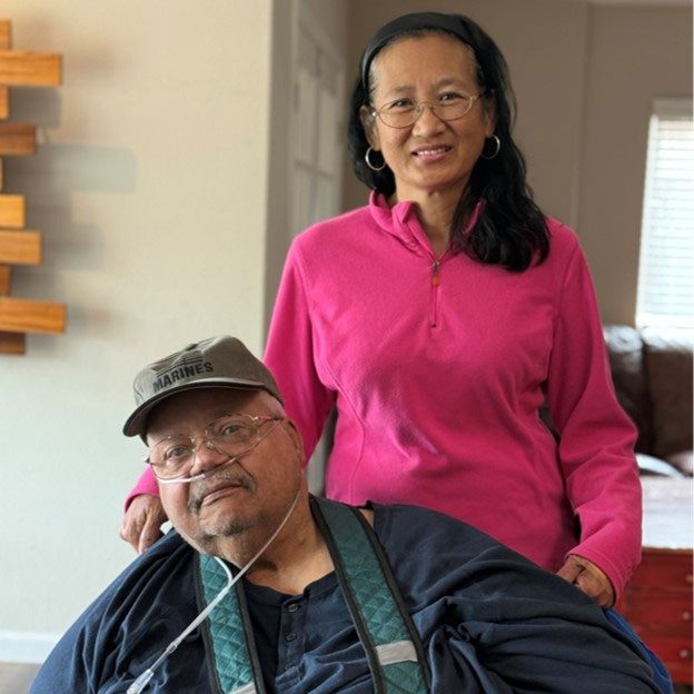 Woman standing behind man in wheelchair.