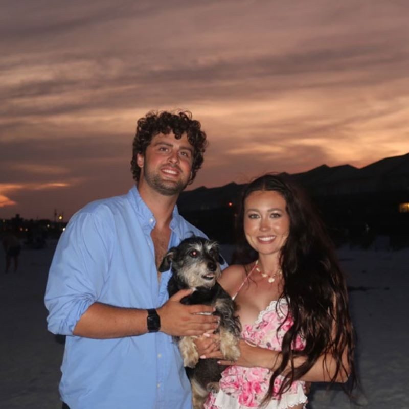 Hannah Jones and Kenny Minasian smiling holding their dog.