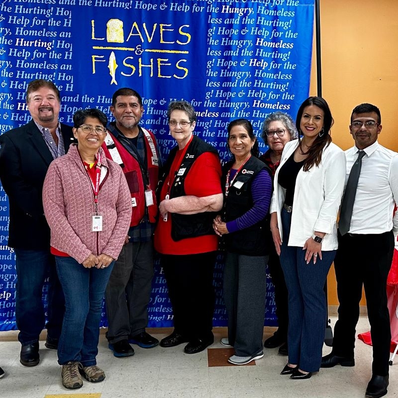 Group of people standing, smiling while posing for a picture.