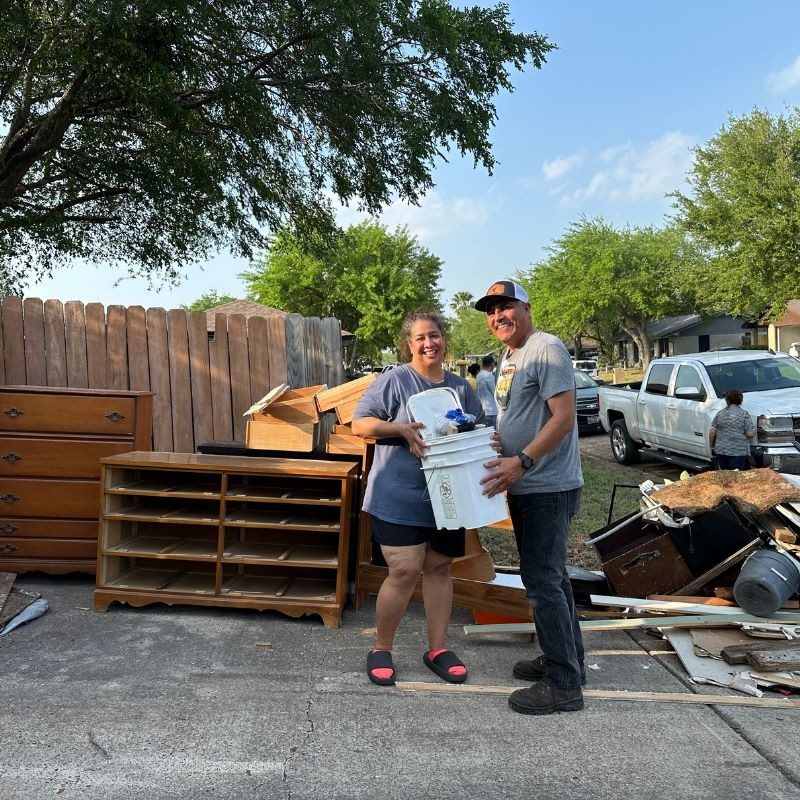 Aida and Felipe Sanchez smiling holding a bucket.