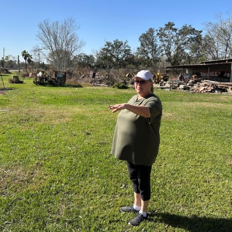 Marci standing and pointing at damaged home.