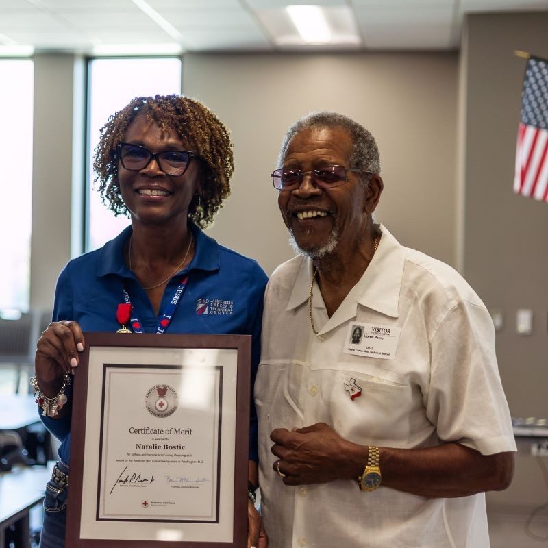 Natalie Bostic holding an award while smiling next to a person.