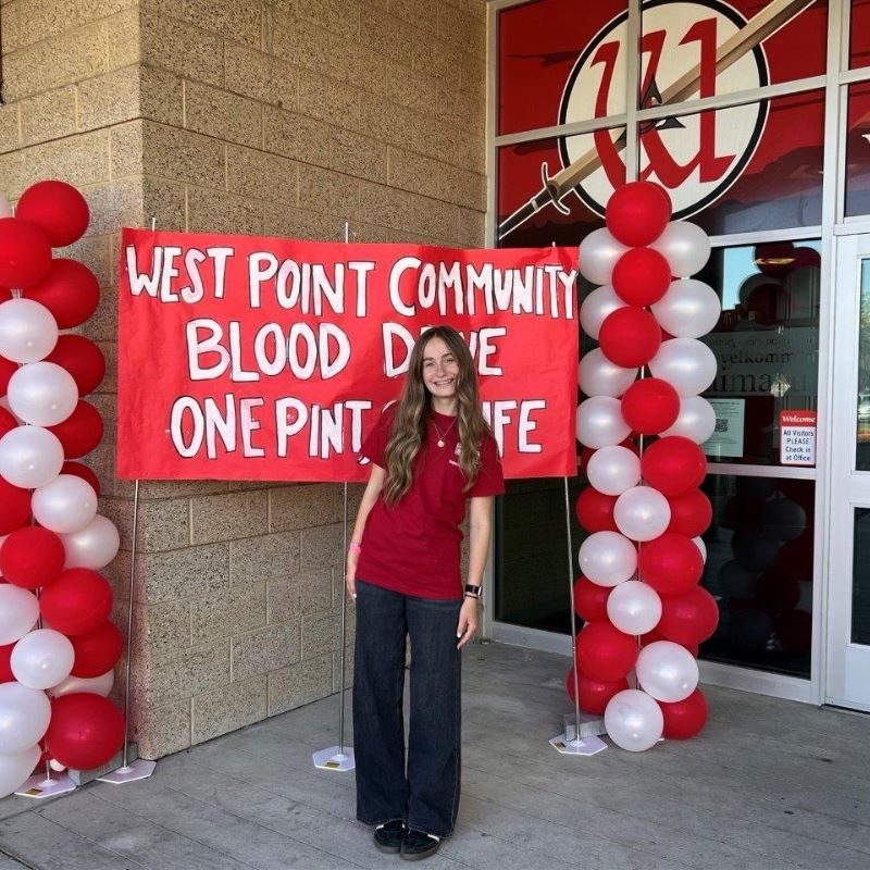 Taytum smiling posing in front of a blood drive poster.