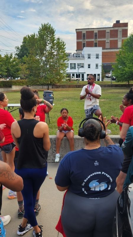 Group of red cross volunteer listening to speaker at a park.