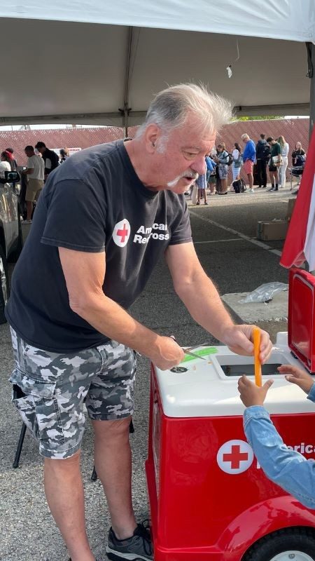 Red cross volunteer Ned serving children ice cream.