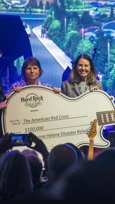 Four people holding life size guitar shaped check.