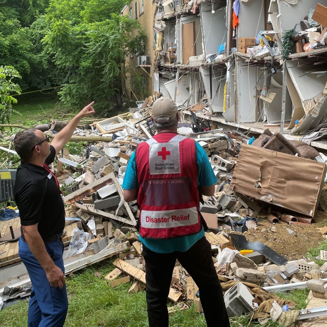 red cross volunteers in front of damaged apartment