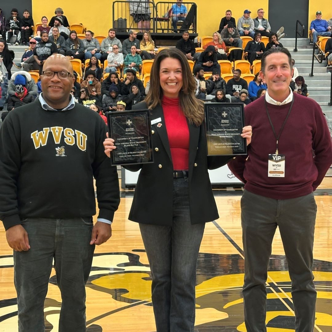 three people at basketball game holding plaques