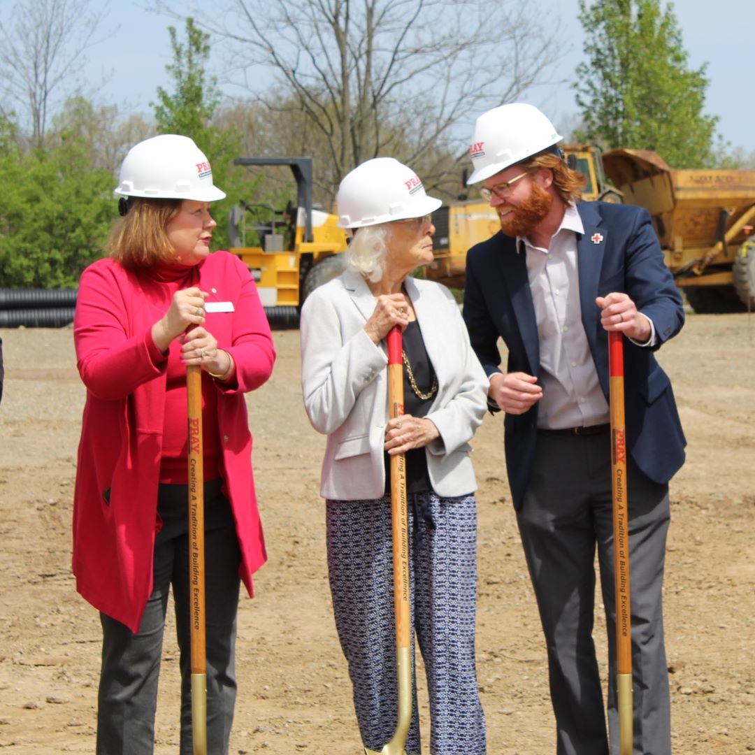 three people in hard hats holding shovels