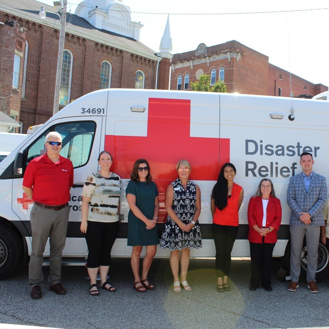 group of people standing in front of Red Cross ERV