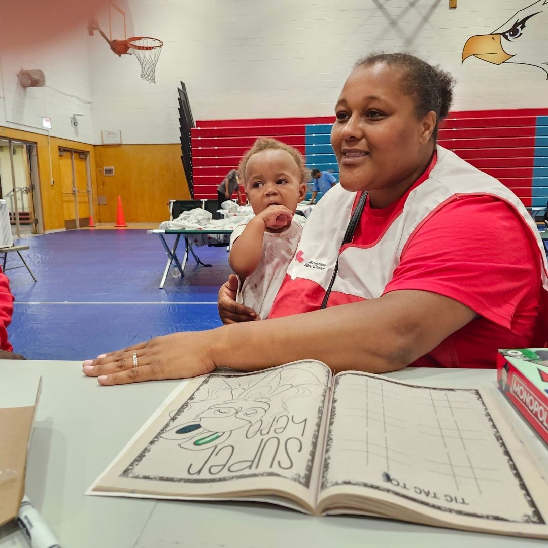 volunteer holding baby in shelter