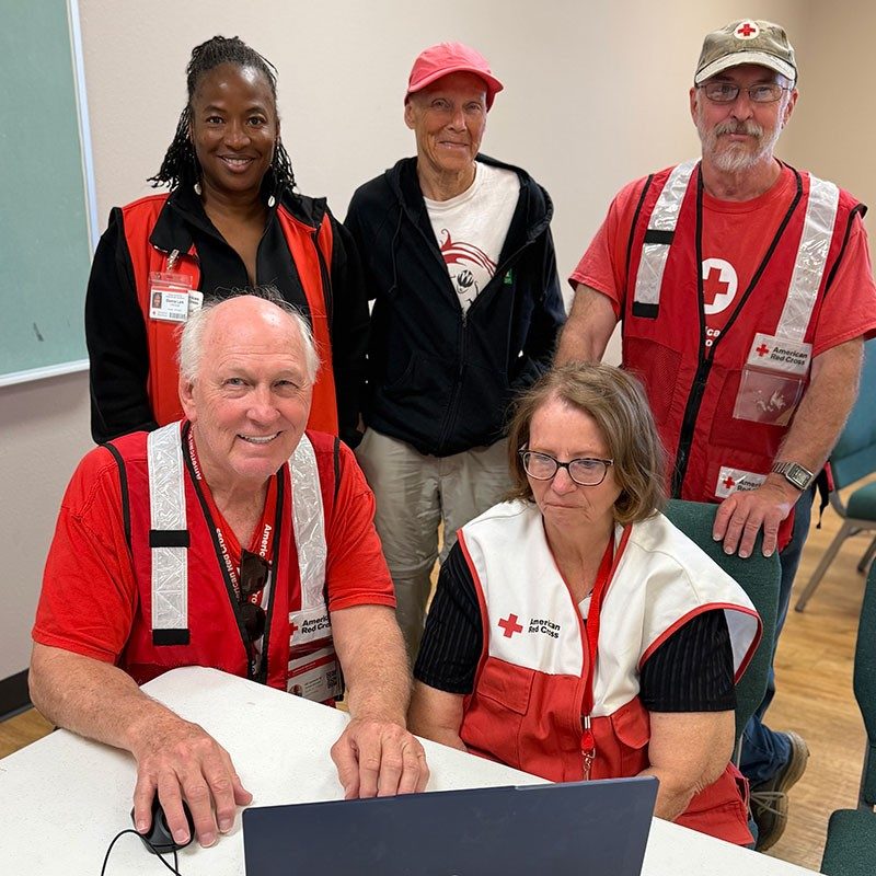 a group of Red Cross volunteers at a desk working on a laptop.