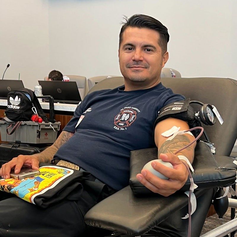 a firefighter sitting in a chair and donating blood.