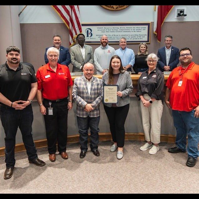 group photo of the Central and South Texas region staff members in a room with one of them holding a framed award.