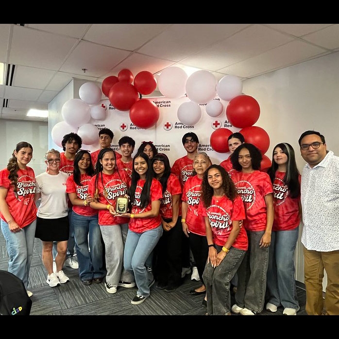 a group picture of Volunteers, two of them holding an award, with balloons in the background.