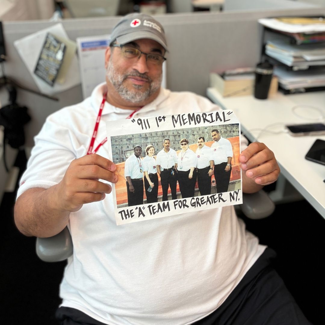 man holding a 9/11 memorial photo of greater new york red cross volunteers