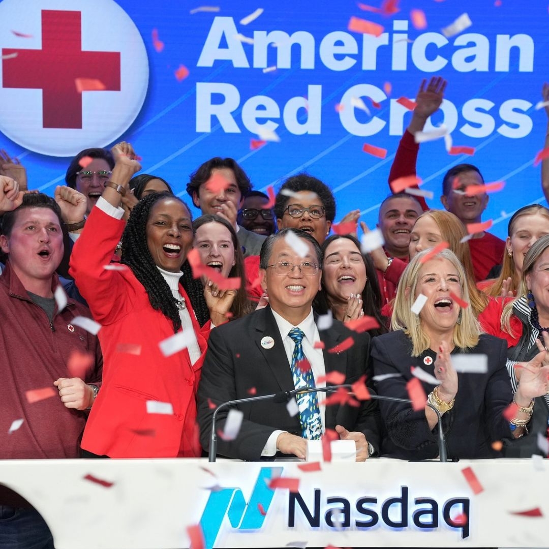 large group of people celbrating with confetti holding a nasdaq banner