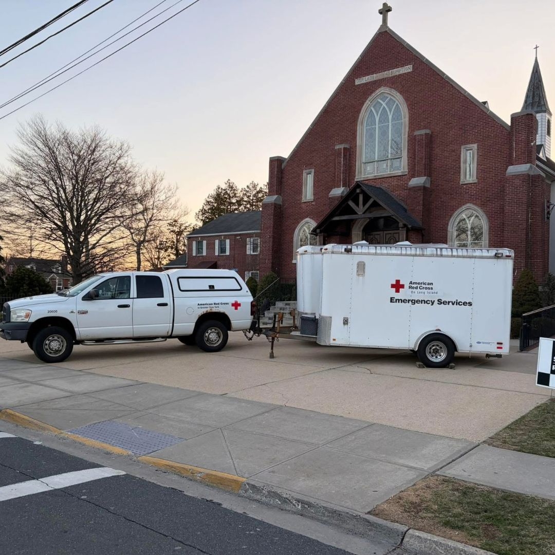 red cross truck and trailer parked in front of church entrance