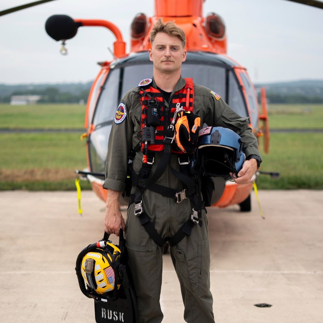 coast guard petty officer scott ruskan in uniform standing in front of helicopter