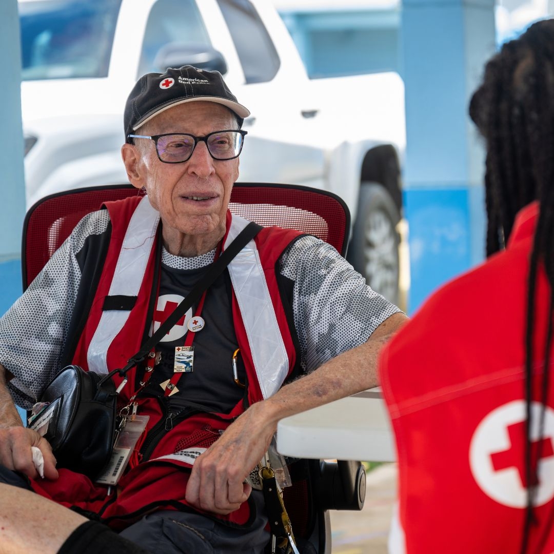volunteer Peter King sitting and conversing with red crosser