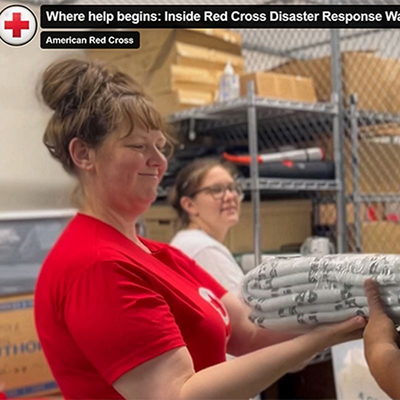 A Red Cross volunteer handing a client a blanket.