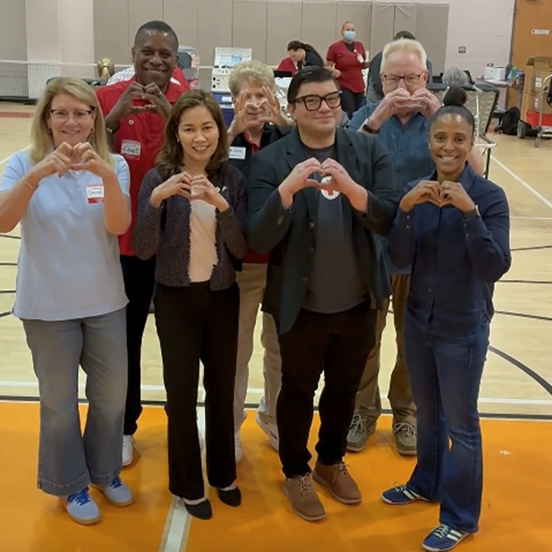 A group of Red Cross blood donors uisng their hands to make hearts.