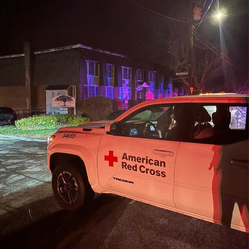 A Red Cross emergency vehicle in front of an apartment building.