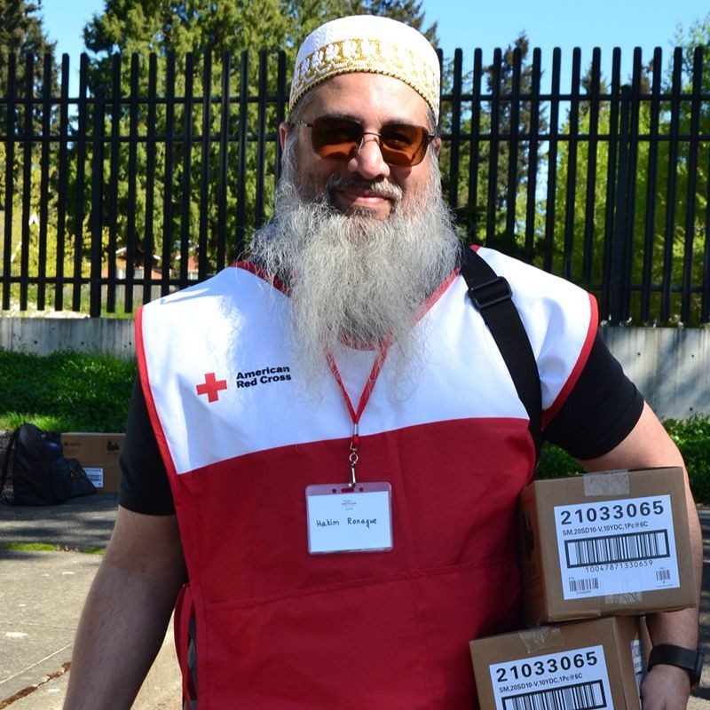 Hakim in a Red Cross vest carrying boxes.